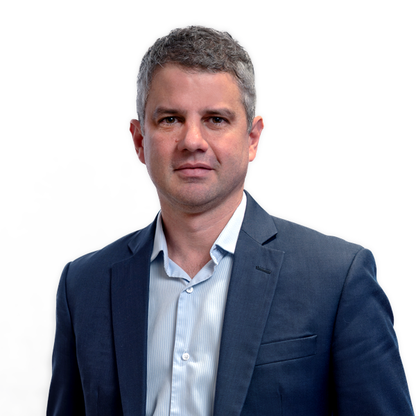 Tomás é um homem branco de cabelo grisalho. Está de terno e camisa branca, sorrindo levemente para a foto.