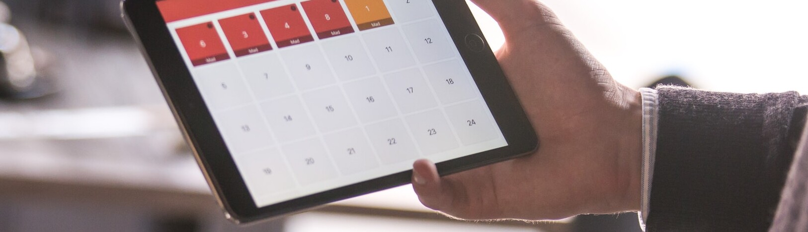 mão segurando um tablet que mostra calendário de datas religiosas