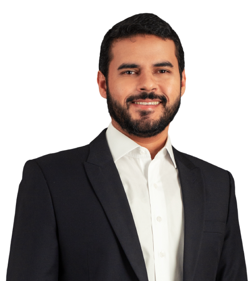 O sócio Bernardo possui cabelos e barbas bem escuros. Na foto, está sorrindo e vestido paletó preto com blusa social branca por baixo.