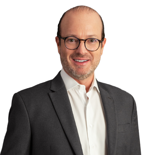Sócio Fabio Ferreira Kujawski está vestindo um paletó cinza escuro e camisa bege claro. Ele tem uma careca com cabelos lisos, curtos e castanho escuro nos lados da cabeça. Ele está com um largo sorriso e usando óculo de grau preto.