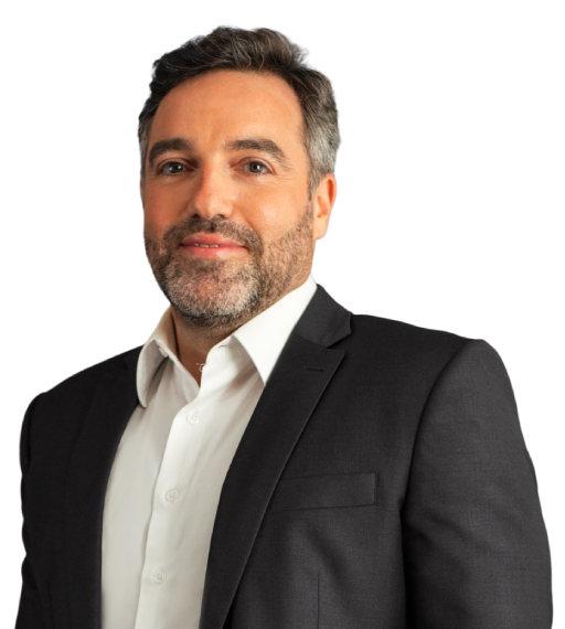 Sócio Fabio Teixeira Ozi está vestindo um paletó cinza escuro e camisa bege claro. Ele tem cabelos lisos, curtos e grisalho. Ele tem barba grisalha e está com um sorriso com a boca fechada.