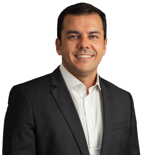 O sócio Thiago Sombra veste um paletó preto com camisa social branca. Seus cabelos são castanho escuro. Na foto, está com um largo sorriso.