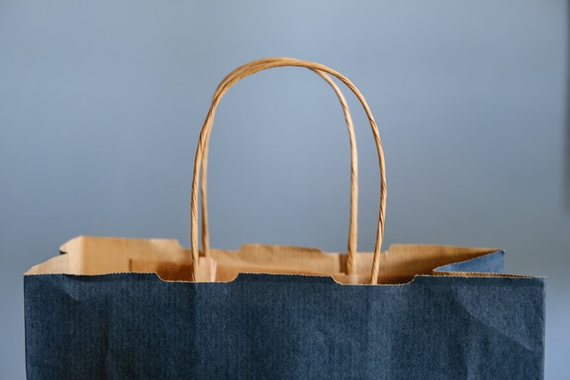 Uma sacola de compra de papelão azul escura em um fundo azul claro