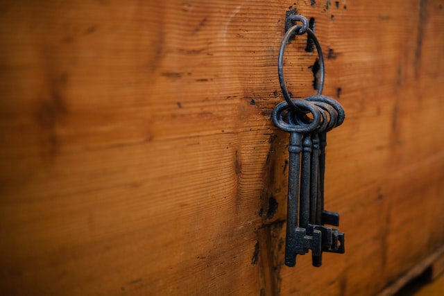 Um chaveiro com 4 chaves de ferro, penduradas em uma porta de madeira