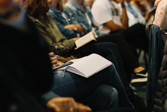 Pessoas reunidas, concentradas, fazendo anotações em conferência