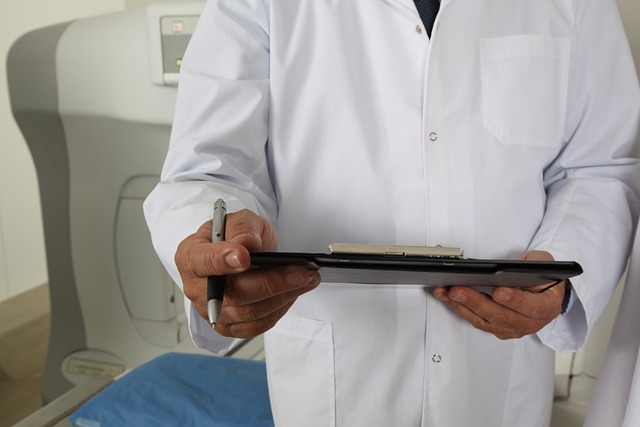 um médico de avental branco. segurando uma prancheta e ao fundo uma máquina de tomografia