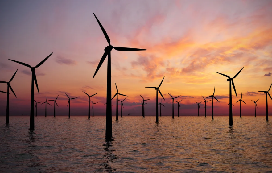 offshore wind power plant in the sea with sunset in the background