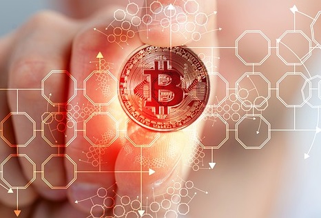 Uma mão segurando uma moeda de bitcoin com imagens que remetem tecnologia surgindo ao redor