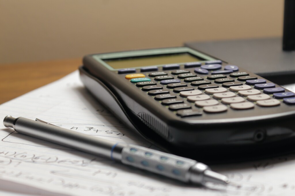 Calculadora e caneta sobre um papel com anotações de números