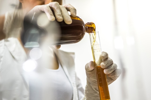Pessoa de jaleco branco preparando medicamentos em laboratório