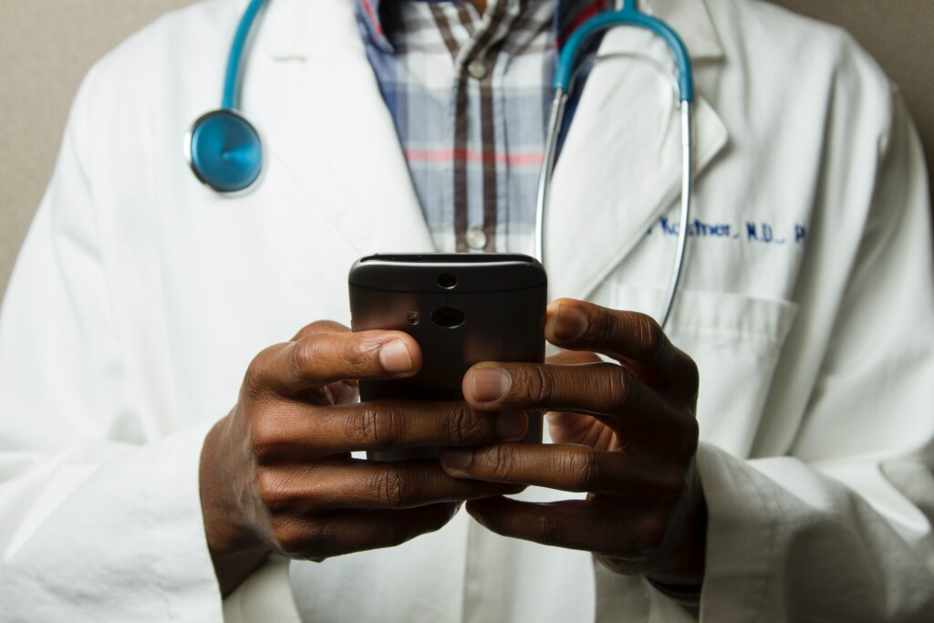 médico que usa jaleco mexe em um celular