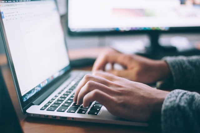 Homem trabalhando em seu escritório e escrevendo em seu notebook.