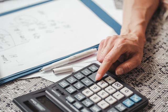 Mão clicando em uma calculadora.