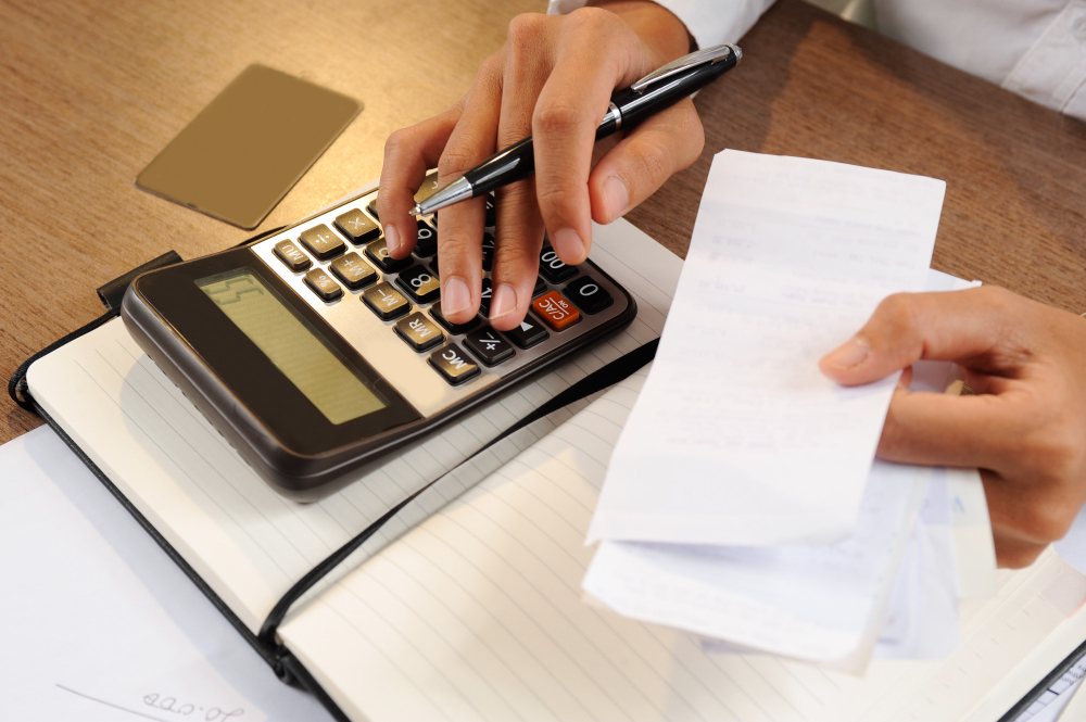Pessoa segurando notas e mexendo em uma calculadora