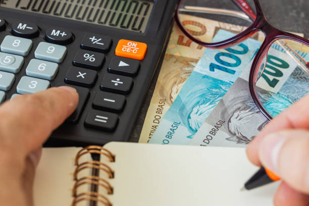 Pessoa usando uma calculadora e escrevendo em um caderno